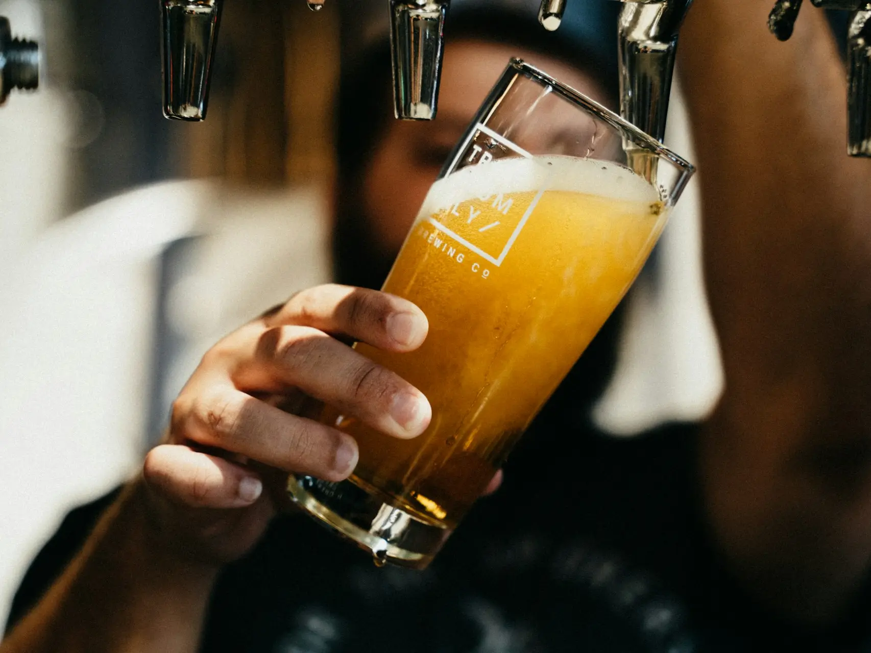 person holding clear drinking glass with yellow liquid