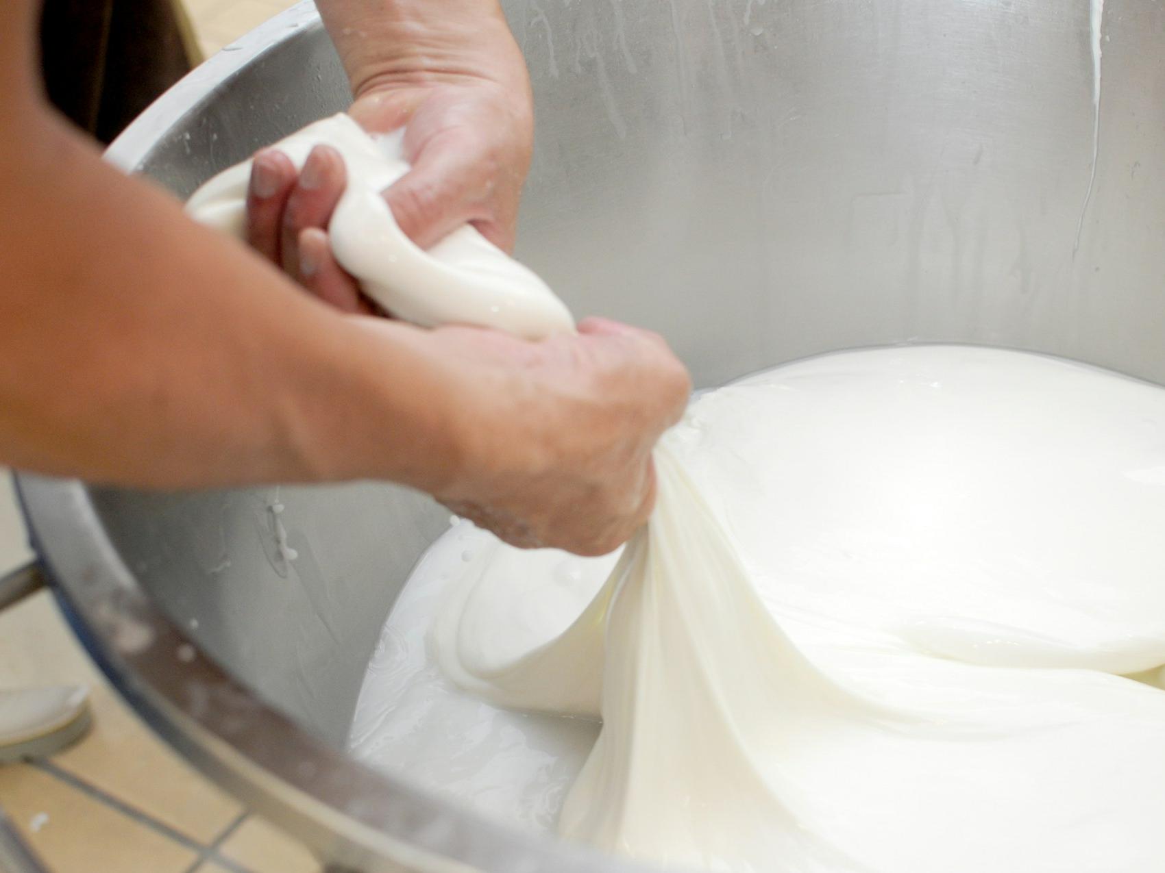 a person is kneading dough in a metal bowl
