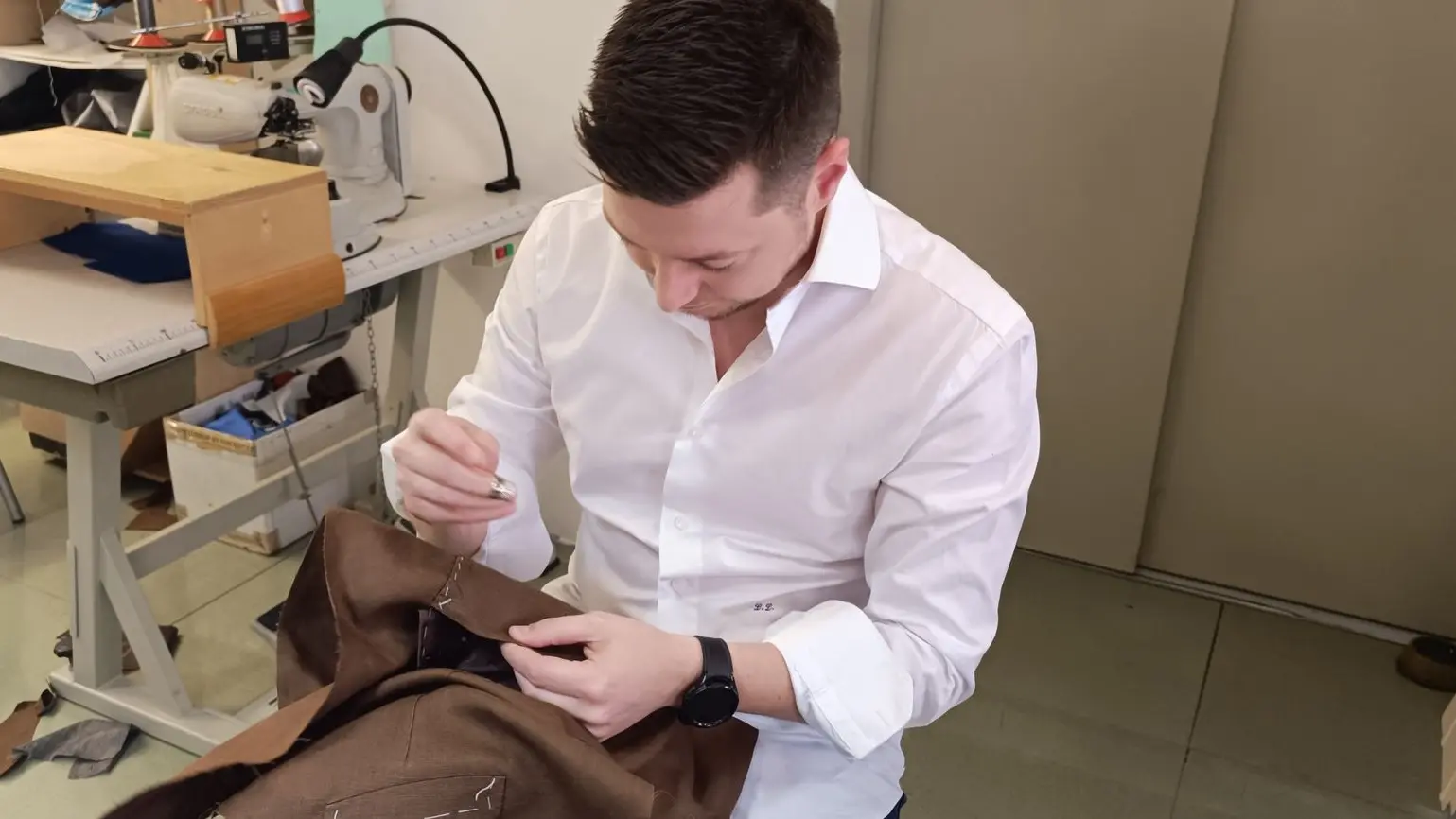 Ragazzo che cuce con ago e filo seduto